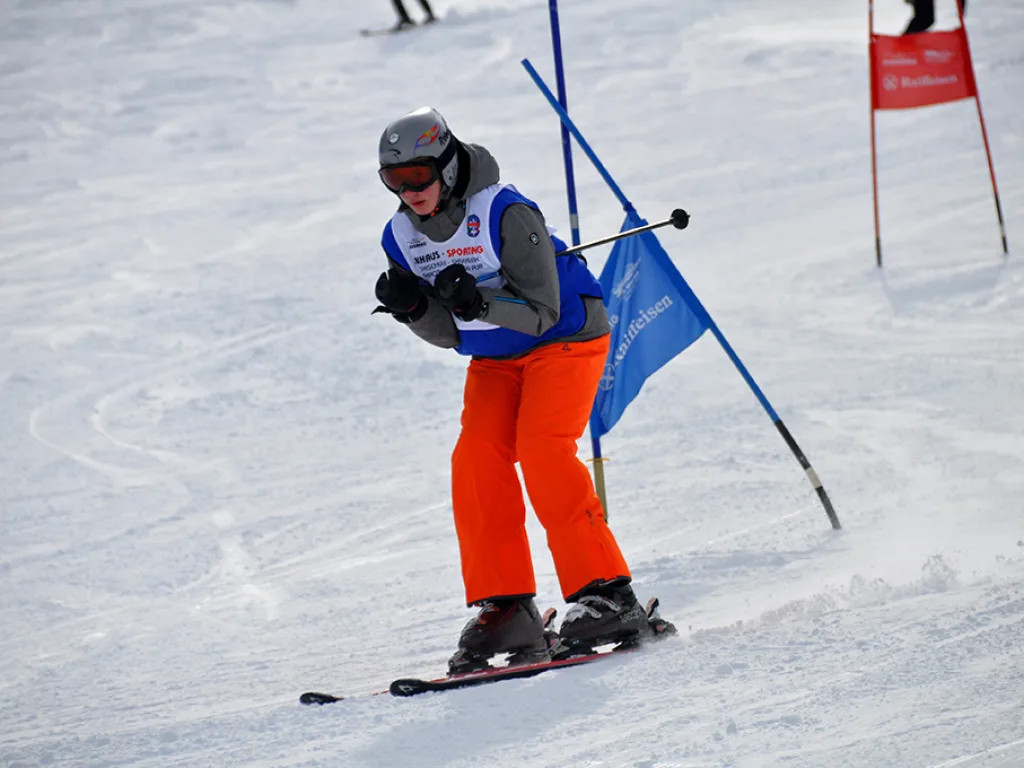 Snowboarder in oranger Hose in tiefer Hocke am Tor.